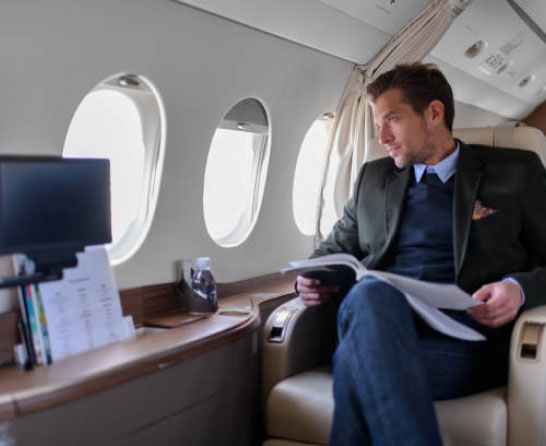 Wealthy man in private jet reading a document and looking out window